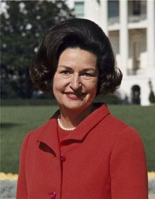 220px-Lady_Bird_Johnson,_photo_portrait,_standing_at_rear_of_White_House,_color,_crop
